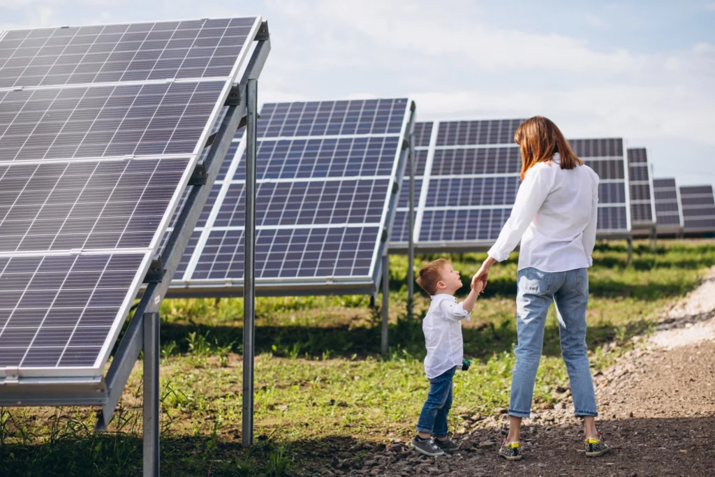 Une mère et son enfant marchent près de panneaux solaires installés au sol, symbolisant un avenir durable